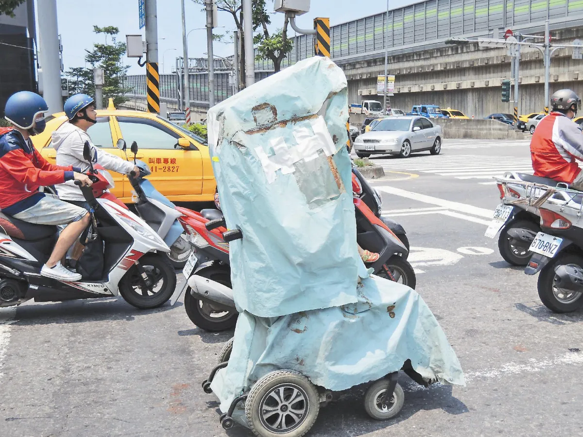 高雄的艷陽讓人受不了，機車騎士穿長袖防曬，一名乘坐電動代步車騎士索性就DIY把車身全用塑膠布包裹，雖然通風效果差了點，但總比曬得頭昏腦脹要好得多。